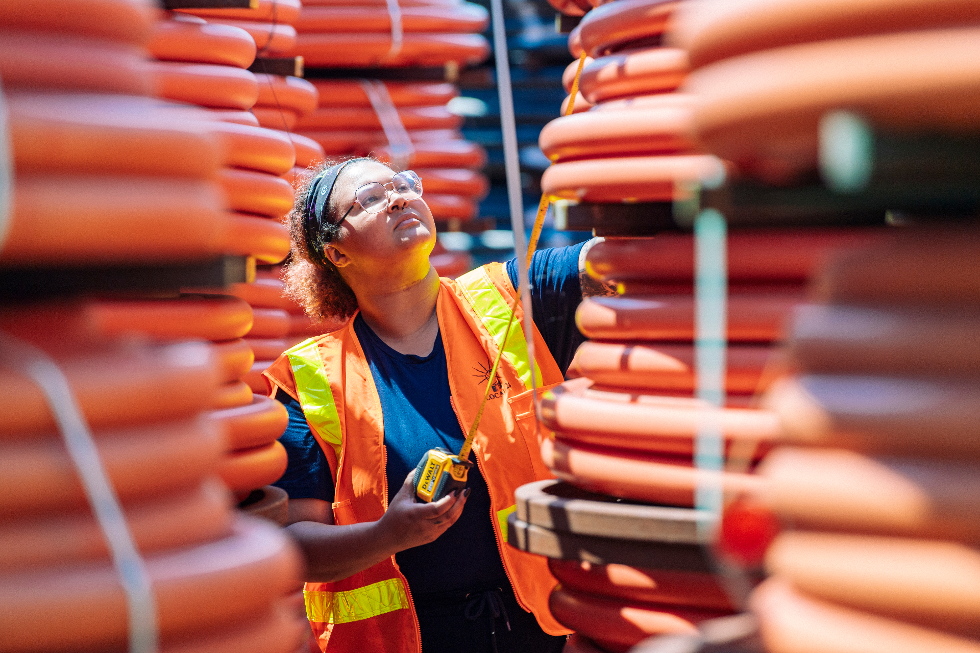 Worker measuring stacked materials in a warehouse.